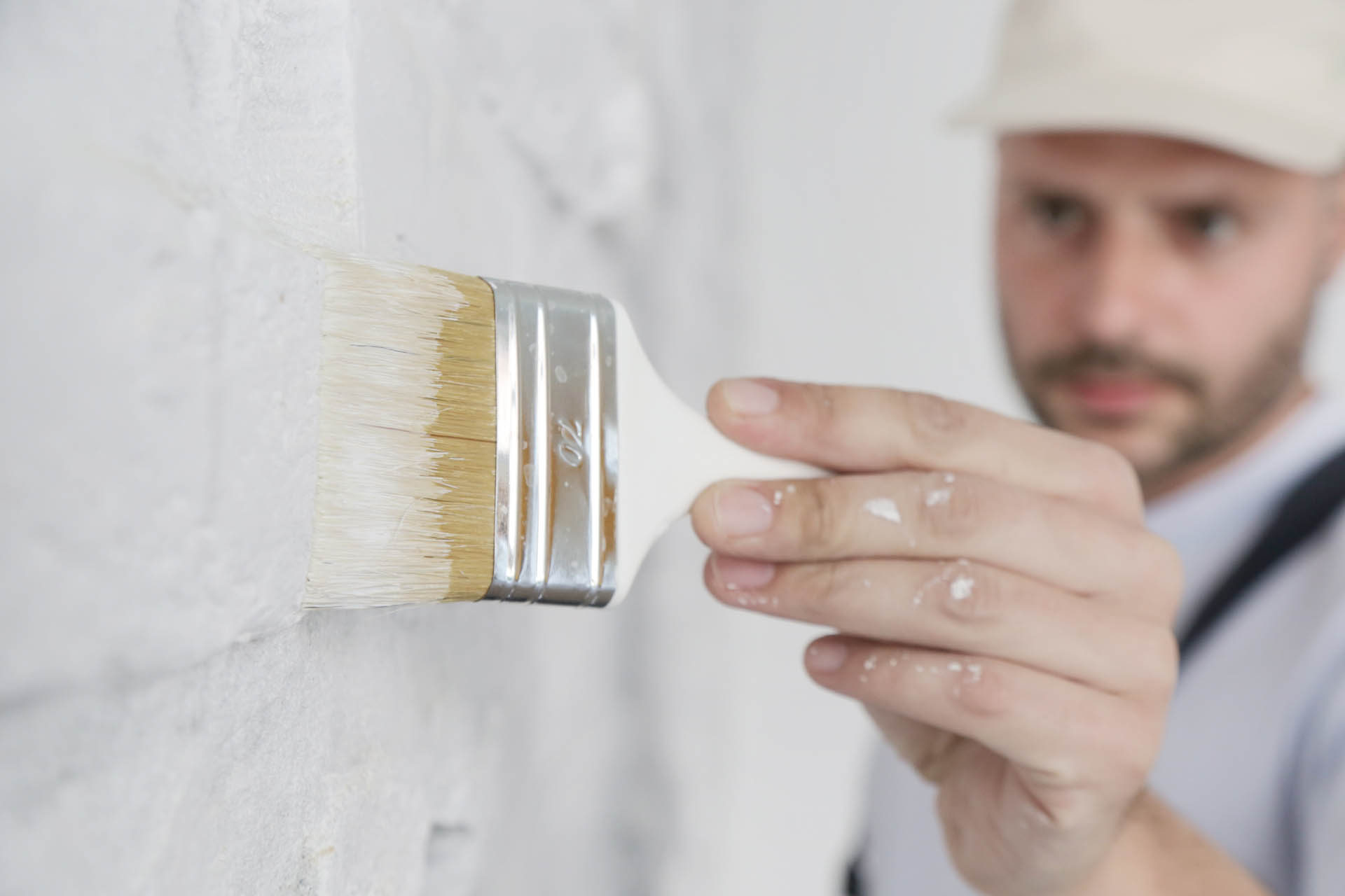 Painting a white brick wall with a paint brush